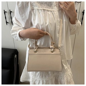 Close-up of beige fashion trend handbag with gold hardware on a model's arm