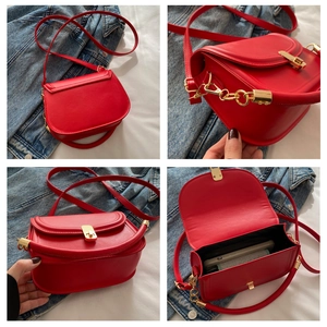 Detail view of red saddle bag featuring gold buckles, interior space and PU leather finish