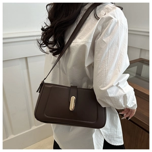 Vue latérale du sac à bandoulière rectangulaire marron foncé avec boucle dorée sur modèle