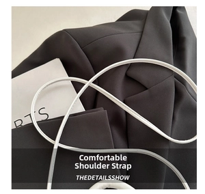 Detail of white leather slim shoulder strap on a black blazer background