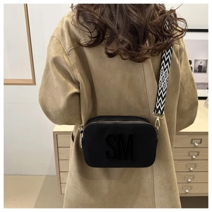 Detailed view of the black camera bag featuring SM logo and geometric strap on model
