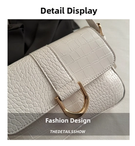 Detailaufnahme der weißen Tasche mit Kroko-Prägung und hochwertiger goldener U-Metallschnalle