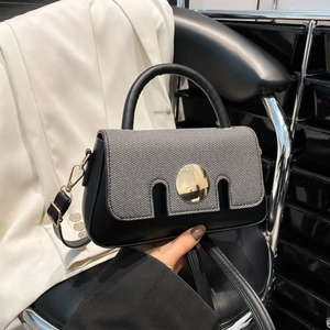 Chic two-tone handbag with grey woven texture flap and gold buckle on a black chair