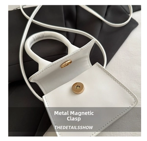 Detail of white mini handbag featuring golden metal magnetic buckle and smooth leather