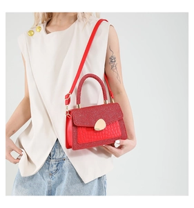 Detail of red crocodile texture handbag with glitter flap and golden metallic hardware