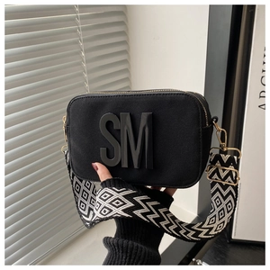 Détail du sac bandoulière noir avec logo SM et large sangle en tissu géométrique