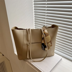 Minimalist beige tote bag with a silk scarf and front zipper pocket on white backdrop