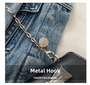 Close-up of light gold chain and lobster clasp on black leather mini crossbody bag