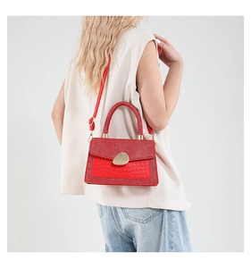 Red crossbody bag with sequin and croc texture detail worn by a model on white background