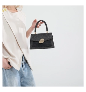 Detail of black croc-embossed leather patch and golden buckle on shiny handbag