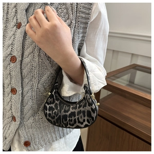 Dettaglio di una mini borsa a mezzaluna con stampa leopardata e accenti dorati eleganti