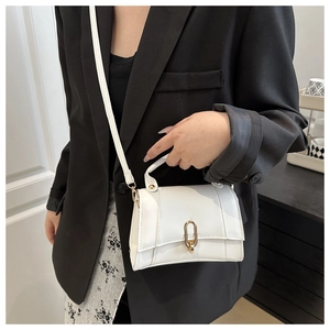 Detail der weißen Mini-Leder-Quadrat-Tasche mit Goldschnalle auf schwarzem Blazer