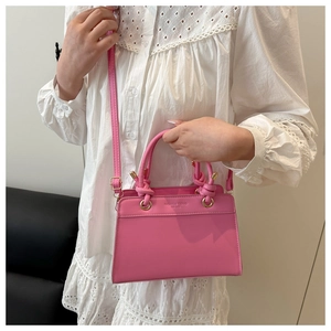 Detail of pink crossbody bag with knotted handles and Fashion Trend text logo