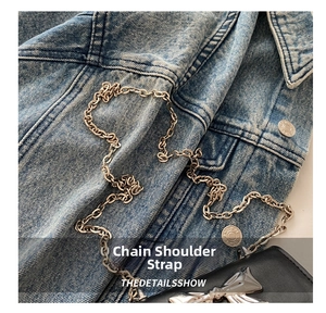 Detail shot of black leather crossbody bag with silver bow buckle on denim jacket