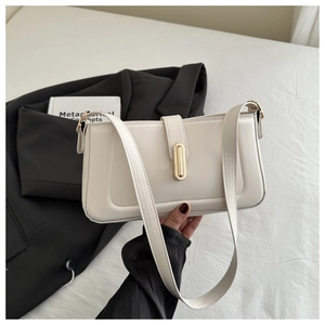 Détail d'un sac à bandoulière en cuir crème avec fermoir doré sur fond de literie blanche