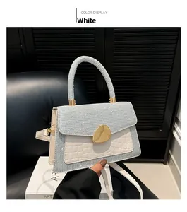 Close-up of white croc-embossed crossbody bag featuring sequins and gold metal buckle