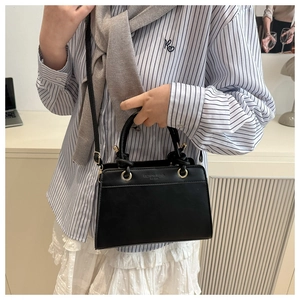 Detail of black faux leather tote bag with gold hardware and knotted handle accents