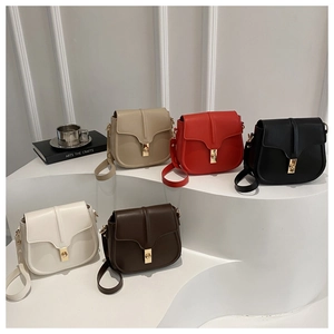 Five assorted vintage saddle bags with gold metal clasps on a white display stand