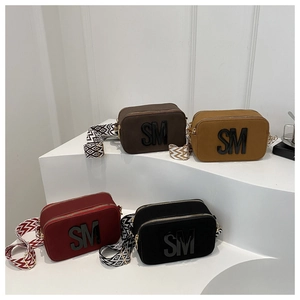 Detail of crossbody camera bags in four colors with wide patterned straps and SM logo