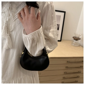 Dettaglio di una borsa a mezzaluna in pelle nera con cerniera dorata in stile lifestyle