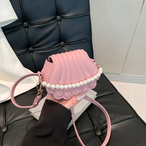Pink shell-shaped crossbody bag with pearl trim and embossed texture held by hand