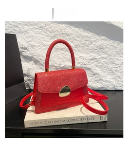 Detail of red crossbody bag with sequins, crocodile texture and golden oval metal lock