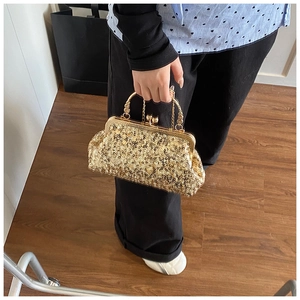 Detailed view of shimmering gold sequin clutch bag with vintage metal handle and clasp