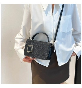 Detail of black sequined crossbody bag with gold hardware and stylish leather handle