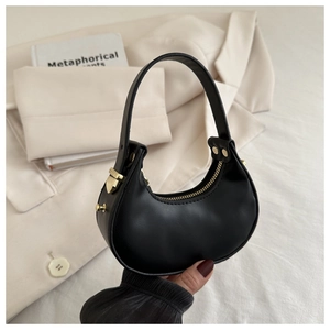 Dettaglio di una borsa a mezzaluna nera con finiture dorate tenuta da una modella