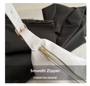 Detail shot of smooth gold zipper on white PU leather shoulder bag with premium texture