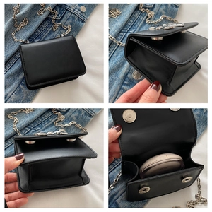 Detail of mini black crossbody bag featuring silver chain strap and metal bow buckle