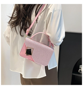 Detailed shot of pink patchwork crossbody bag with metallic accents on white shirt