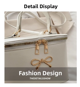 Close-up of cream box bag featuring a golden bow buckle and dual zipper details