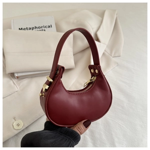 Dettaglio di una mini borsa a mezzaluna bordeaux in pelle liscia con zip e finiture dorate