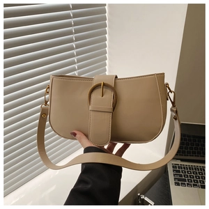 Détail d'un sac baguette beige avec boucle ronde en métal et similicuir lisse