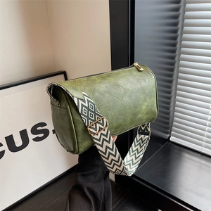 Dunkelgrüne Boston-Zylindertasche mit geometrischem Web-Schultergurt in Lifestyle-Ansicht