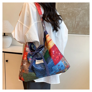 Back view of a model carrying a large bohemian patchwork denim tote bag with vibrant patterns