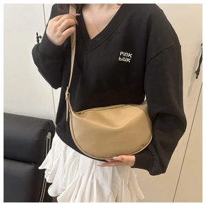 Detailed lifestyle view of a beige minimalist half-moon crossbody bag with leather strap