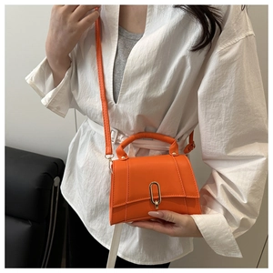 Detail der leuchtend orangefarbenen Ledertasche mit Metallverschluss und Trageriemen