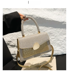 Detailed close-up of a gold glitter mini bag with crocodile texture and metal lock