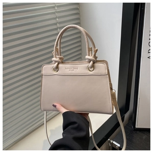 Detailed close-up of fashion trend leather handbag featuring gold buckles and debossed text