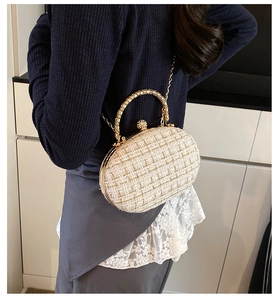 Detail of elegant cream tweed evening bag with gold metallic handle and ball clasp closure