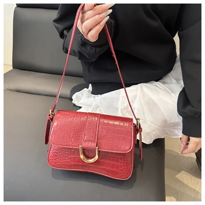 Detail einer roten Handtasche aus Krokodilleder mit goldener Hufeisenschnalle