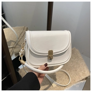 Detail of creamy white saddle bag showing gold hardware lock and smooth leather texture