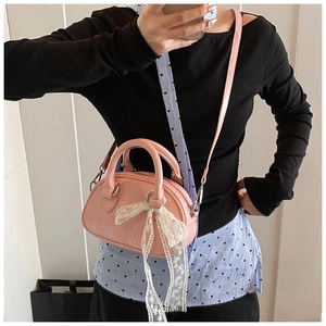 Mirror selfie showing a pink leather crossbody bag with lace bow and cartoon embossing