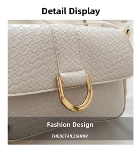 Close-up of cream woven texture and golden U-shaped metal buckle on the leather bag