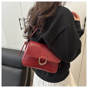Detail der roten Handtasche mit Krokodilmuster und goldener D-Ring-Schnalle am Model
