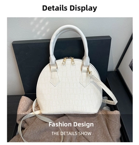 Close-up of white crocodile pattern shell bag with gold zippers and metal hardware details