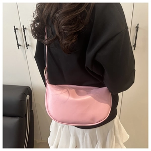 Pink crescent crossbody bag shown on shoulder to display size and soft matte texture