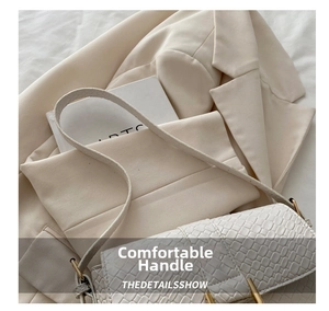 Detail of white crocodile pattern handbag featuring a gold buckle and luxury embossed texture
